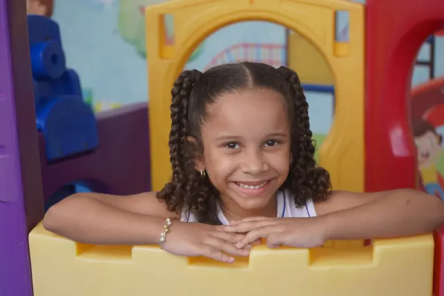 Aluna sorrindo em espaço de convivência da escola